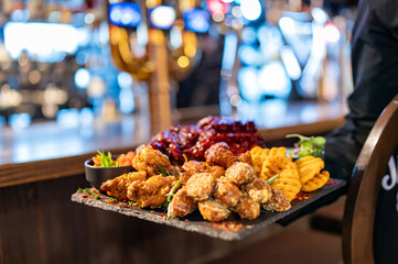 Waiter hold plate with set of assorted grilled meat platter with differend chicken and vegetables in restaurant