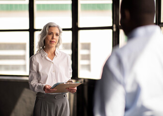 Female Headhunter Meeting With Employee Holding Folder In Modern Office