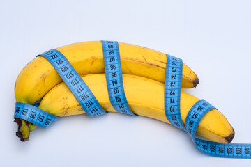 Świeże owoce banany owinięte centymetrem krawieckim na jasnym tle - obrazy, fototapety, plakaty
