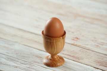 Soft-boiled egg in wooden egg cup  on white background.