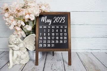 May 2023 monthly calendar on easel stand on wooden background