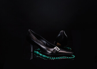 Art photo - necklace with modej shoes on dark background