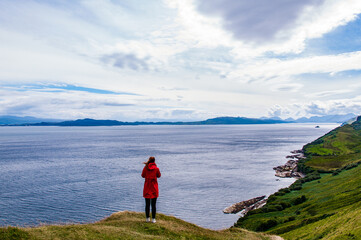 Fototapeta na wymiar A woman standing on a cliff and looking at the landscape in Scotland