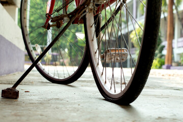 Fototapeta na wymiar Closeup view of vintage bike which has flat wheels and parked on cement floor of downstairs of the building, soft focus.