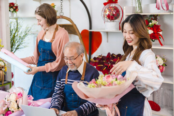 Elder senior man florist talking on smartphone using laptop at florist.portrait of mature male small business owner using laptop and looking at camera in flower shop