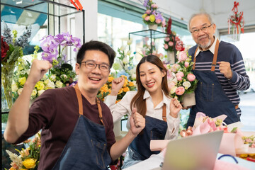 Asian man florist talking on smartphone using laptop at florist.portrait of mature male small business owner using laptop and looking at camera in flower shop