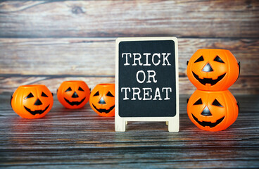 Trick or treat text message with Halloween Pumpkin bucket on wooden background