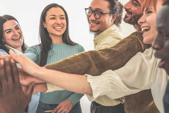 Group of happy coworkers holding hands encouraging each other before meeting