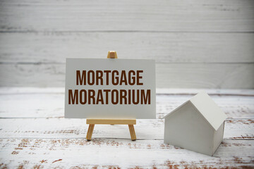 Mortgage moratorium text message and house model on wooden background