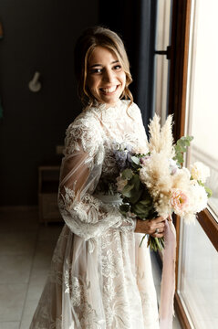 a positive bride in a beautiful wedding dress with lace is in a hotel room and is waiting for a meeting with the groom. beauty wedding day.