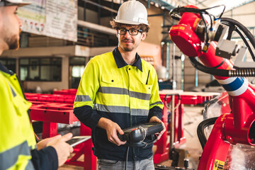 Fototapeta premium Factory worker with safety uniform discussion about robot arm working in factory workplace.