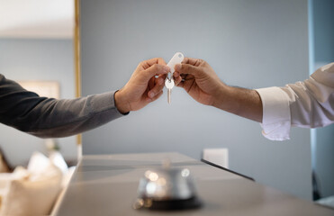 Unrecognizable Hotel Receptionist Giving Key To Guest At Reception, Closeup