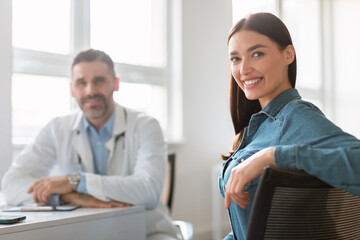 Portrait of happy female patient receiving medical consultation with male doctor, lady looking and smiling at camera