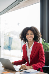 Female african sitting at the desk, looking to camera.