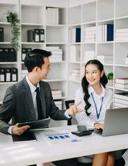 Two business workers talking on the smartphone and using laptop at the office.