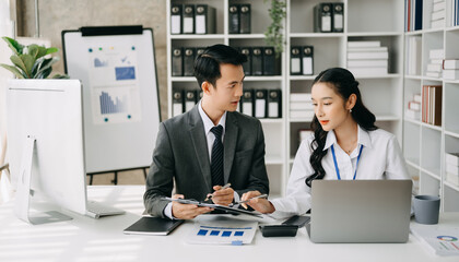 Two business workers talking on the smartphone and using laptop at the office.