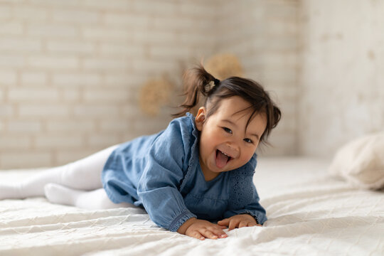 Adorable Korean Infant Girl Laughing Lying On Bed At Home