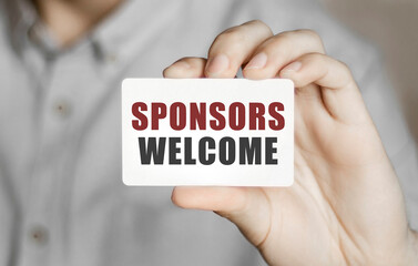 Card with text SPONSORS WELCOME in a man's hand