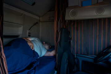 Trucker sleeping in the truck bed, with the cabin curtains drawn, in his off-time.