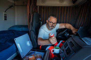 Trucker in the truck cabin with the fridge open and preparing a coffee in his off-time.