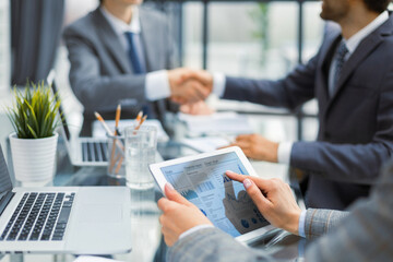 Cropped shot of a group of businesspeople looking at graphs on digital tablets