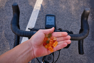 Sports snack for cyclist.Jelly gummy bears in the hand of a cyclist against the background of a...