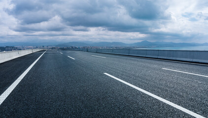 Asphalt road and urban skyline on the seaside