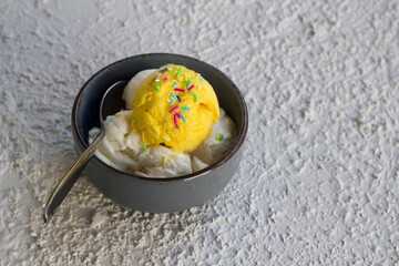 Mixed, slightly melted ice cream balls, in a gray bowl, with an ice cream spoon