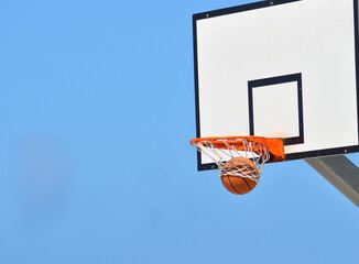 Basketball hoop of the sky, outdoor game with a ball going inside the basket © ajcsm