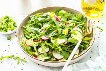 Green salad with spinach, arugula, radish with olive oil and seeds.