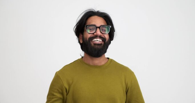Portrait of cheerful bearded young man showing v sign of peace and looking at camera while standing isolated against white background