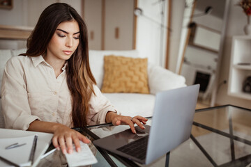 Serious busy smart millennial european female manager typing on computer, check bill, finance, pay taxes