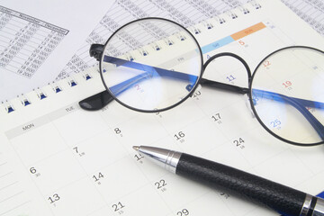 Naklejka na ściany i meble Black round eyeglasses and pen on calendar page. Time and planning business concept.