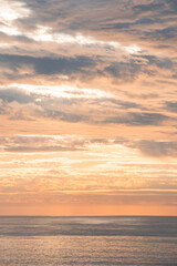 Fototapeta premium Last rays of the sun illuminate clouds flying across the sky and the reflection from the sea illuminates the surrounding cliffs. Harmony of colours. Dreamscape. Sunset in the Algarve region, Portugal
