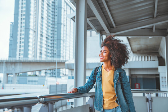 Happy young tourist African American woman with backpack smiling while stand in train station, Enjoying travel concept