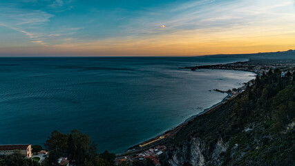Panorama of the beach of Taormina, Sicily. Exciting sunset oversicilian sea seen from the terrace of the city, on the southern slopes of the Peloritani mountains, ionian coast, near Etna volcano.