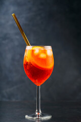 Aperol Spritz cocktail on dark background. Cocktail Aperol Spritz with oranges and ice in glass with eco-friendly glass straw