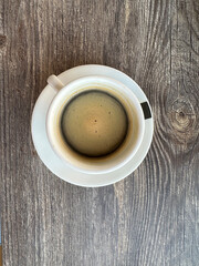 Top view of white cup of black coffe on wooden background. Flat lay simple composotion