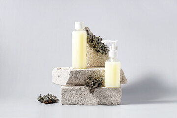containers for cosmetics on the podium made of stone and lichens on a gray background