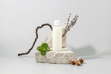 cosmetics container on the podium made of stone, lavender twigs and mint leaves on a gray background