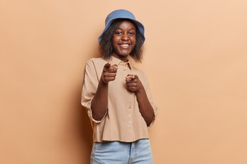 Positive teenage girl with dark skin points at you at camera expresses best choice and says I...