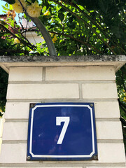 Blue sign with white number seven hanging on a brick wall