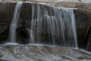 Obraz premium Stream Of Water Washes Over Edge Of Boulder Along The Tuolumne River
