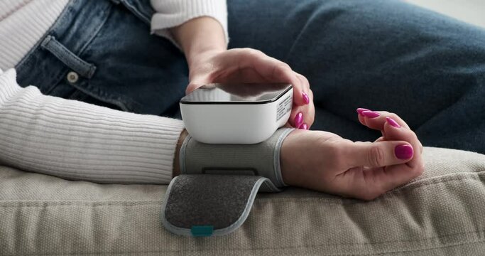 Woman lying on couch measuring blood pressure at home with an electronic monitor. Emphasizing the ease and convenience of self-monitoring, the video promotes regular check-ups and preventative care.
