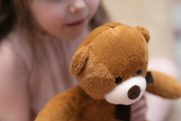 A girl, a brunette of seven years with a teddy bear in her hands.