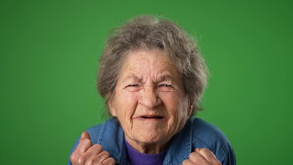 Portrait of toothless frustrated angry with despair upset hands raised in air portrait of elderly mature old woman 80s isolated on green screen background.