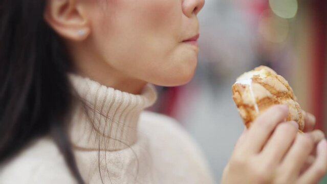 4K Happy Asian woman eating Japanese sweet bread during travel at Sensoji Temple in Asakusa, Tokyo, Japan. Attractive girl enjoy and fun urban outdoor lifestyle travel city street on holiday vacation.