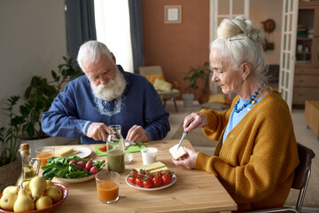 Fototapeta na wymiar Senior family having breakfast together sitting at table in the living room at home