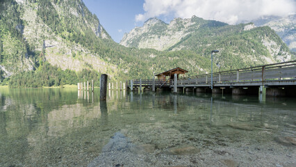 Wooden pier located on alpine lake surrounded by mountains, Konigssee, Germany