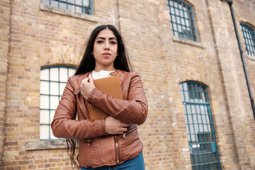 Indian woman is holding a book against her chest.